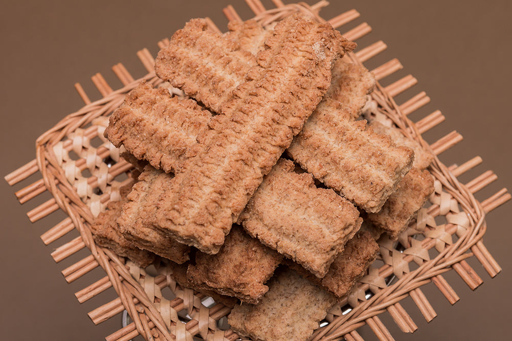 Fluted butter biscuits stacked on a woven mat